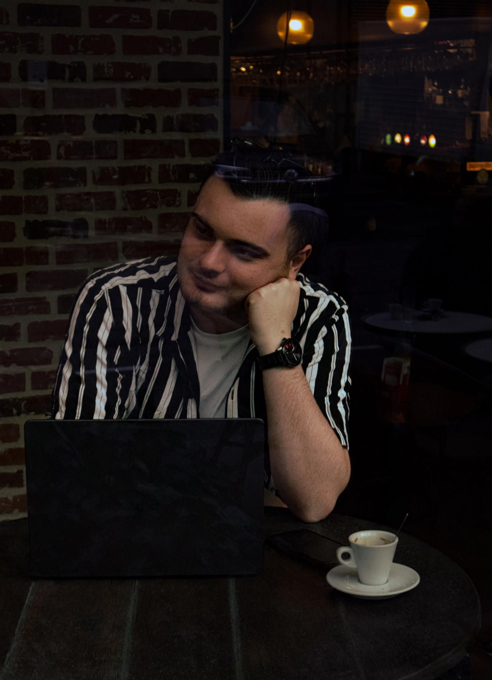 Photo d’ambiance montrant un développeur travaillant dans un café avec son laptop et une tasse de café, atmosphère chaleureuse et urbaine.